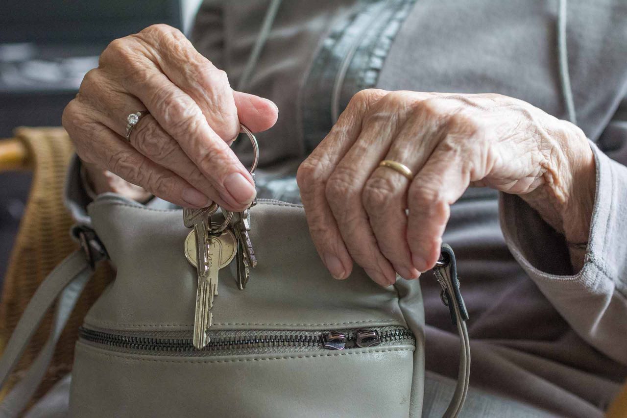 Una persona de la tercera edad sosteniendo su bolso