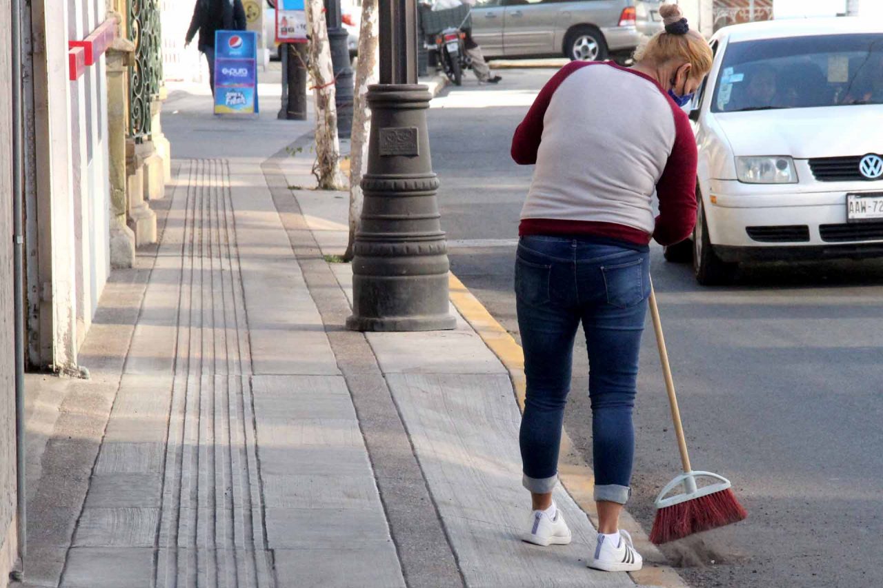 Empleada doméstica barriendo la calle